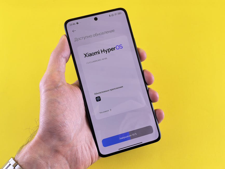 Close-up of a hand holding a smartphone displaying Xiaomi HyperOS update screen on a yellow background.
